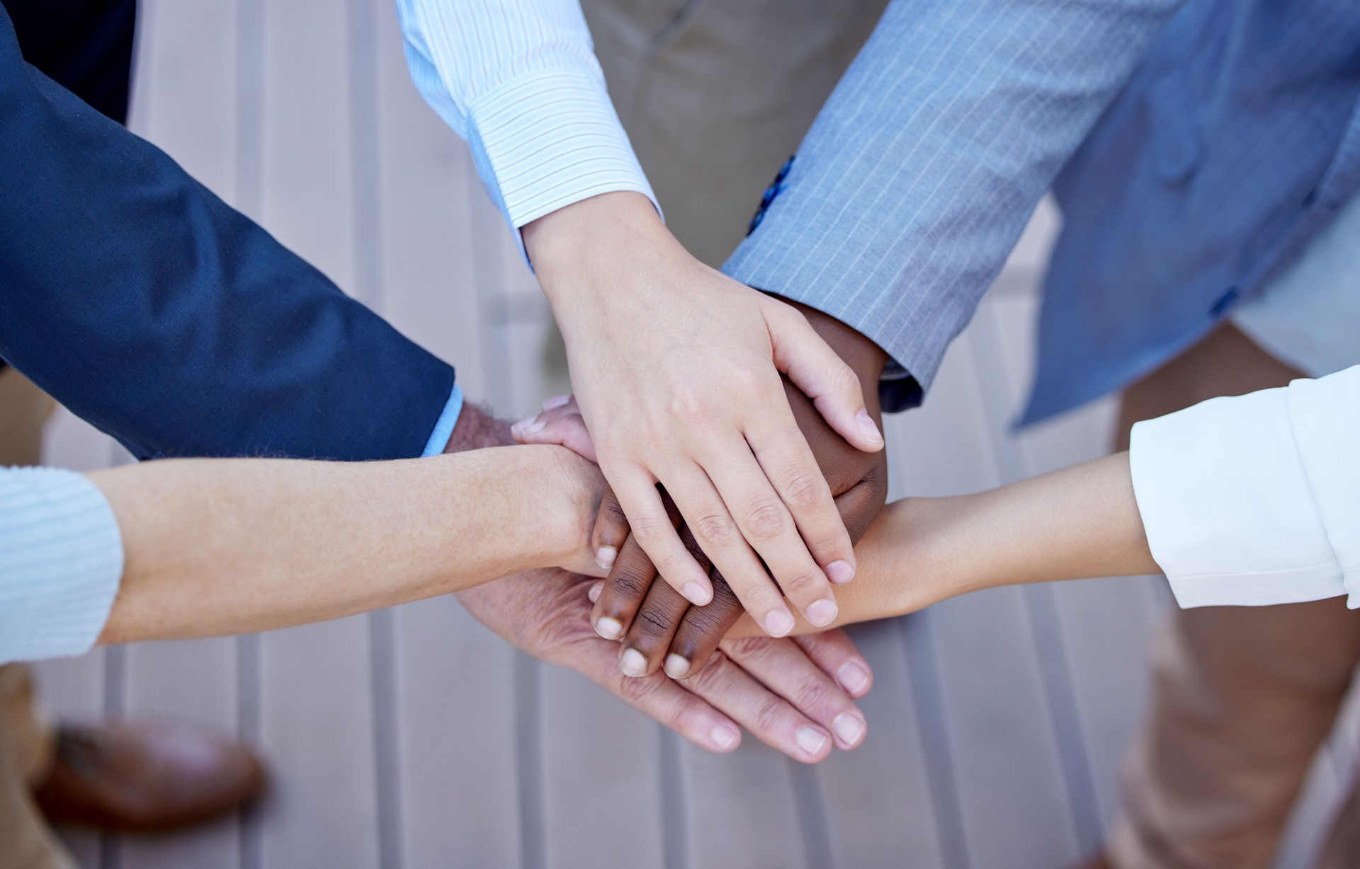 High angle shot of a group of unrecognizable businesspeople standing outside with their hands in a huddle